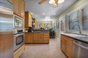 Kitchen with dark countertops, appliances with stainless steel finishes, light tile patterned floors, a peninsula, and recessed lighting
