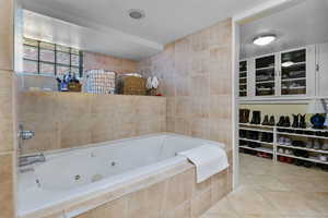 Full bath featuring tile walls, tile patterned floors, and a whirlpool tub