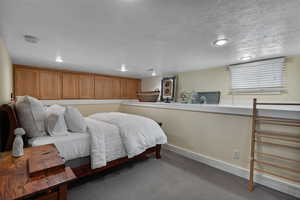 Bedroom with dark carpet and a textured ceiling
