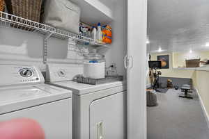 Laundry room featuring a textured ceiling and washing machine and dryer