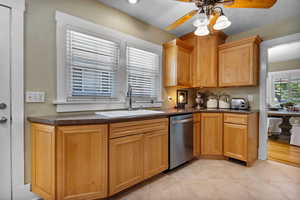 Kitchen featuring a ceiling fan, dishwasher, light tile patterned floors, and a textured wall
