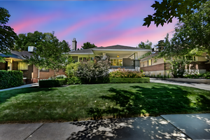 View of front of house with a lawn, a balcony, and stucco siding