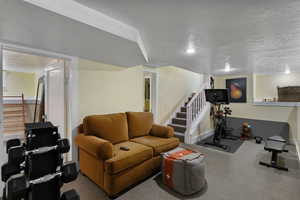 Living area with stairs, a textured ceiling, and carpet