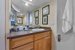 Bathroom with a textured wall, vanity, and a textured ceiling