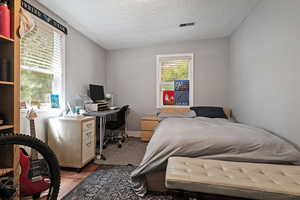 Bedroom with an office area, wood finished floors, and a textured ceiling