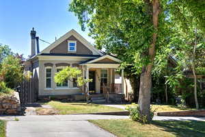 View of front of property with covered porch, a chimney, and brick siding