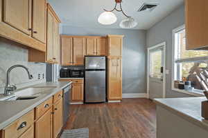 Kitchen featuring tasteful backsplash, stainless steel appliances, dark wood-style floors, pendant lighting, and light brown cabinets