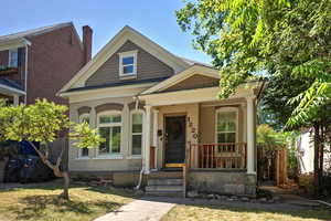 View of front facade with a porch, a front lawn, brick siding, and a chimney