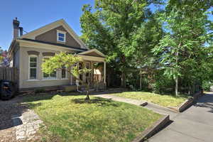 View of front of house featuring a front lawn, a chimney, a porch, and brick siding