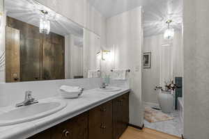 Full bath featuring double vanity, light wood finished floors, a bath, and decorative backsplash