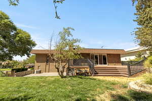 Back of property featuring brick siding, a deck, roof with shingles, and stairs