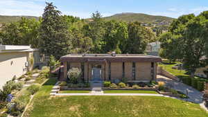 Mid-century home with a front yard, a mountain view, brick siding, and a porch