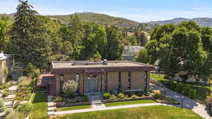 View of front facade with a mountain view, brick siding, and a front yard