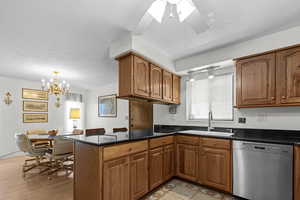 Kitchen featuring brown cabinets, dishwasher, a textured ceiling, dark stone countertops, and a chandelier