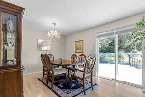Dining space featuring light wood finished floors, a chandelier, and a textured ceiling