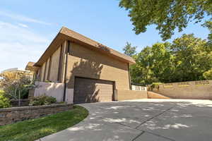 View of home's exterior featuring concrete driveway, brick siding, and mansard roof