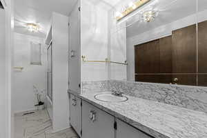 Bathroom featuring vanity, combined bath / shower with glass door, and light marble finish floors