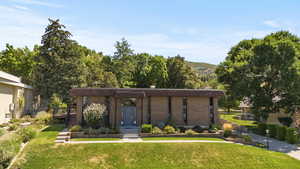 Mid-century modern home featuring a front yard, brick siding, and a wooden deck