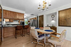 Dining room with light wood-type flooring, a ceiling fan, and a chandelier