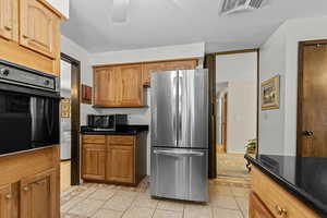 Kitchen featuring stainless steel appliances, light tile patterned floors, and dark stone countertops