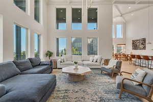 Living area featuring light wood-style flooring, beam ceiling, ornamental molding, and a high ceiling