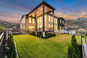 Back of house at dusk with a fenced backyard, a trampoline, and a mountain view