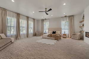 Bedroom with carpet floors, a ceiling fan, a glass covered fireplace, and recessed lighting