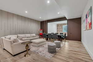 Living area featuring light wood finished floors, recessed lighting, wood walls, and a decorative wall