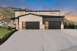 Modern home with concrete driveway, a mountain view, stone siding, and an attached garage