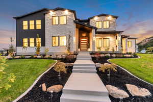 Contemporary home featuring a yard, stone siding, and covered porch