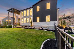 Back of house at dusk featuring stone siding, stucco siding, and a patio