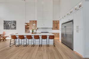 Kitchen featuring pendant lighting, a kitchen bar, built in fridge, a large island, and decorative backsplash