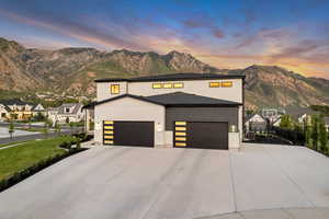 Modern home featuring a mountain view, driveway, an attached garage, and stone siding