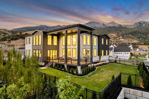 Back of property at dusk with a mountain view and a fenced backyard