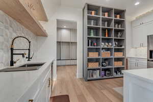 Kitchen featuring backsplash, light wood-style flooring, light stone countertops, recessed lighting, and stainless steel fridge with ice dispenser