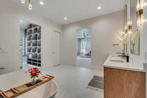 Ensuite bathroom with recessed lighting, double vanity, ceiling fan, a freestanding bath, and light tile patterned flooring