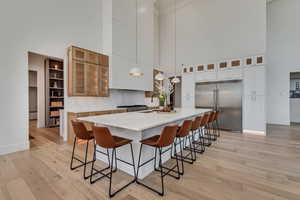 Kitchen with hanging light fixtures, decorative backsplash, a large island, a breakfast bar area, and a high ceiling