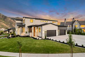 View of front facade featuring a garage, concrete driveway, a lawn, and stone siding
