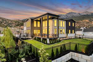 Back of house at dusk with a mountain view and a fenced backyard