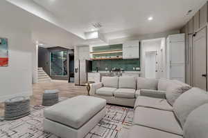 Living area featuring light wood-style flooring, stairway, and recessed lighting