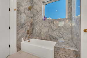 Full bathroom featuring a combined bath / shower with marble appearance