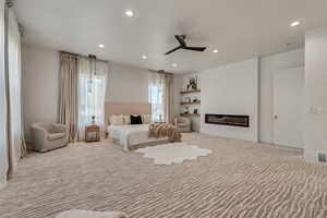 Bedroom with a glass covered fireplace, carpet flooring, a ceiling fan, and recessed lighting