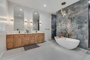Bathroom featuring tile walls, a soaking tub, double vanity, and recessed lighting