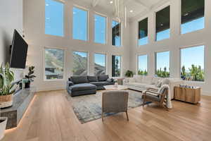 Living room featuring light wood-style floors, beam ceiling, healthy amount of natural light, a towering ceiling, and recessed lighting