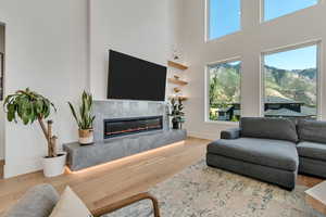 Living room featuring light wood-style floors, a premium fireplace, and a high ceiling