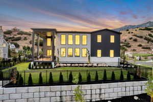 Back of property at dusk with a fenced backyard and a patio