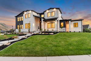 Contemporary house with stone siding, a front yard, and a mountain view