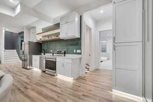 Kitchen featuring white cabinetry, open shelves, stainless steel appliances, backsplash, and recessed lighting