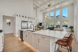 Kitchen featuring white cabinetry, beam ceiling, pendant lighting, light wood finished floors, and coffered ceiling