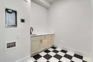 Laundry room with dark floors, washer hookup, and cabinet space